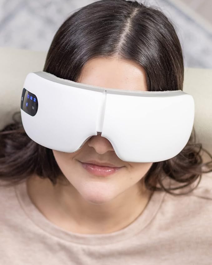 Woman using white electric eye massager with digital display, designed with heat, vibration, and air pressure functions to relieve eye strain and promote relaxation