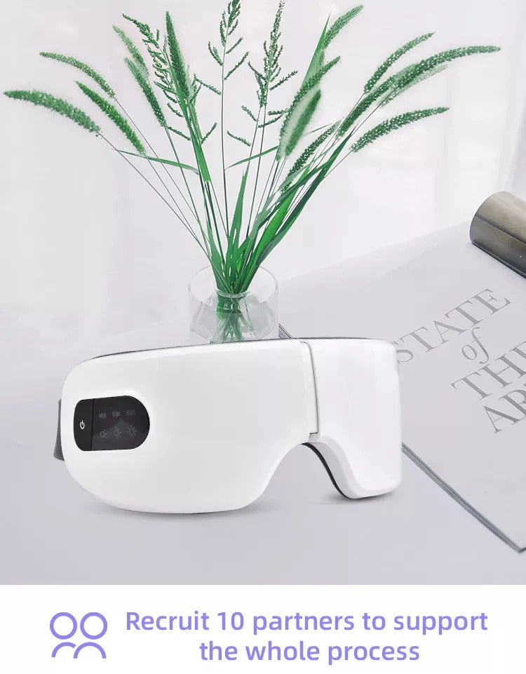 White smart electric eye massager with digital control panel placed on table, designed for heat, vibration, and air pressure massage to relieve eye strain and fatigue